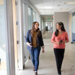 2 women standing near white wall