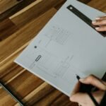 a person holding a pen over a piece of paper