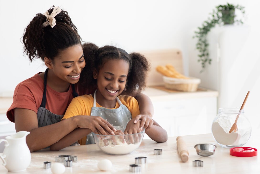 Loving black mother and daughter cooking together