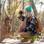 Serious woman trains dog holding treat trophy for exemplary behavior, accurate execution of commands