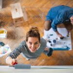 Top view of couple painting wall indoors at home, relocation and diy concept