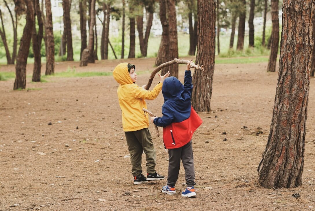 a couple of kids standing next to each other in a forest
