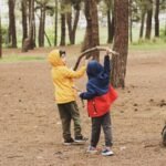 a couple of kids standing next to each other in a forest