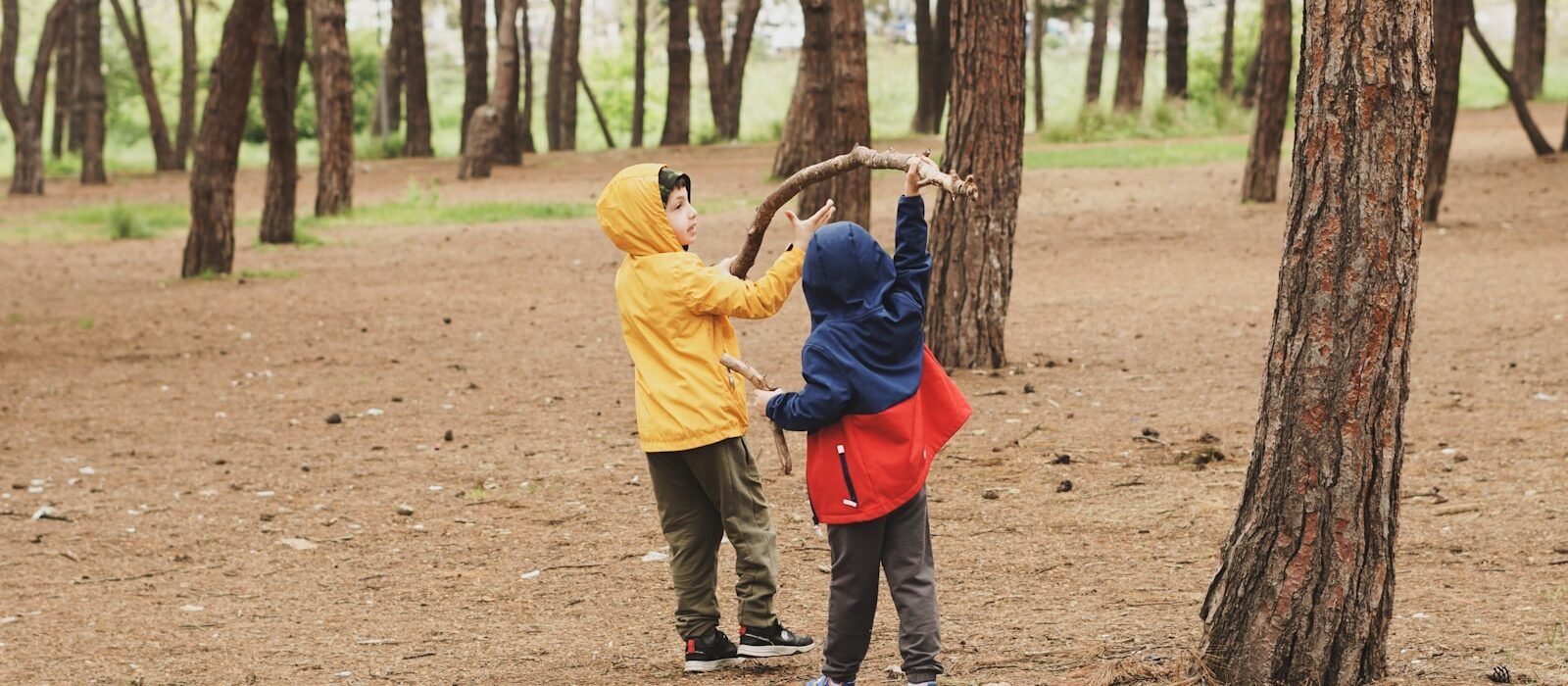 a couple of kids standing next to each other in a forest