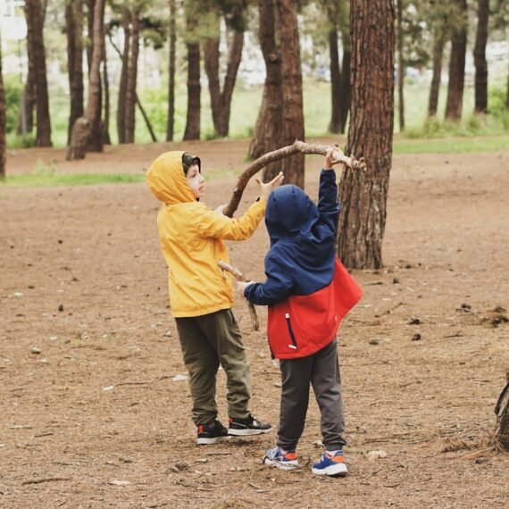 a couple of kids standing next to each other in a forest